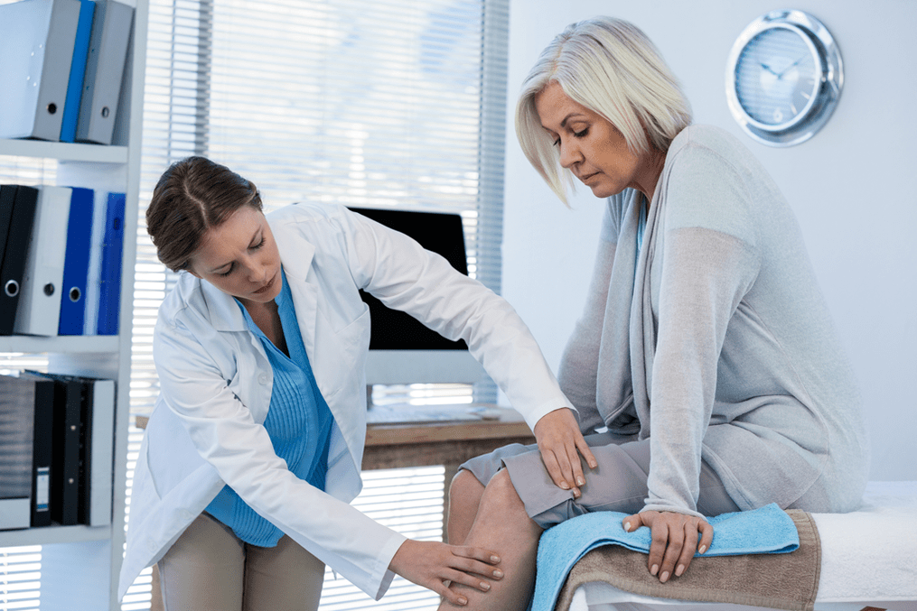 Doctor examines a patient with arthrosis of the knee joint